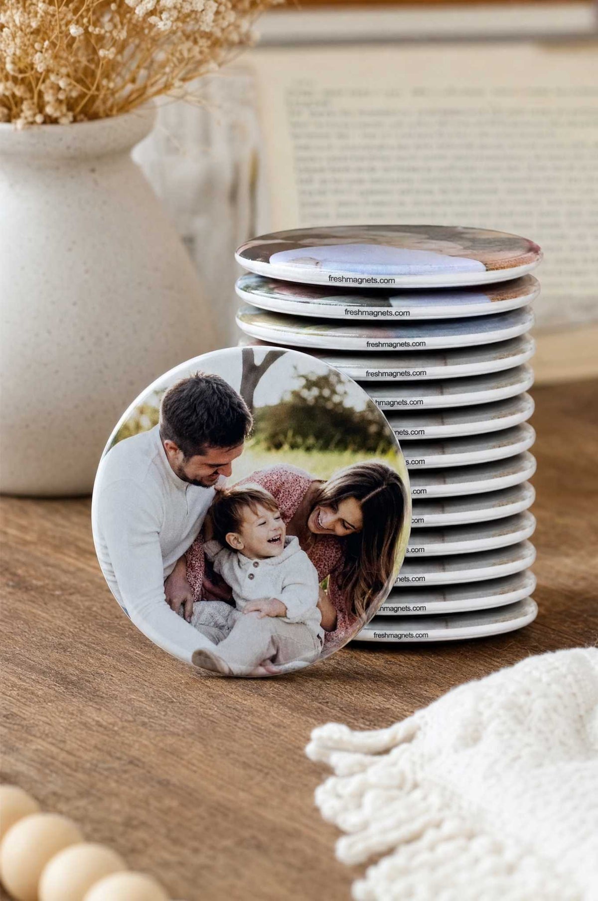 A stack of 2.25 inch round photo magnets with a family photo magnet leaning in front