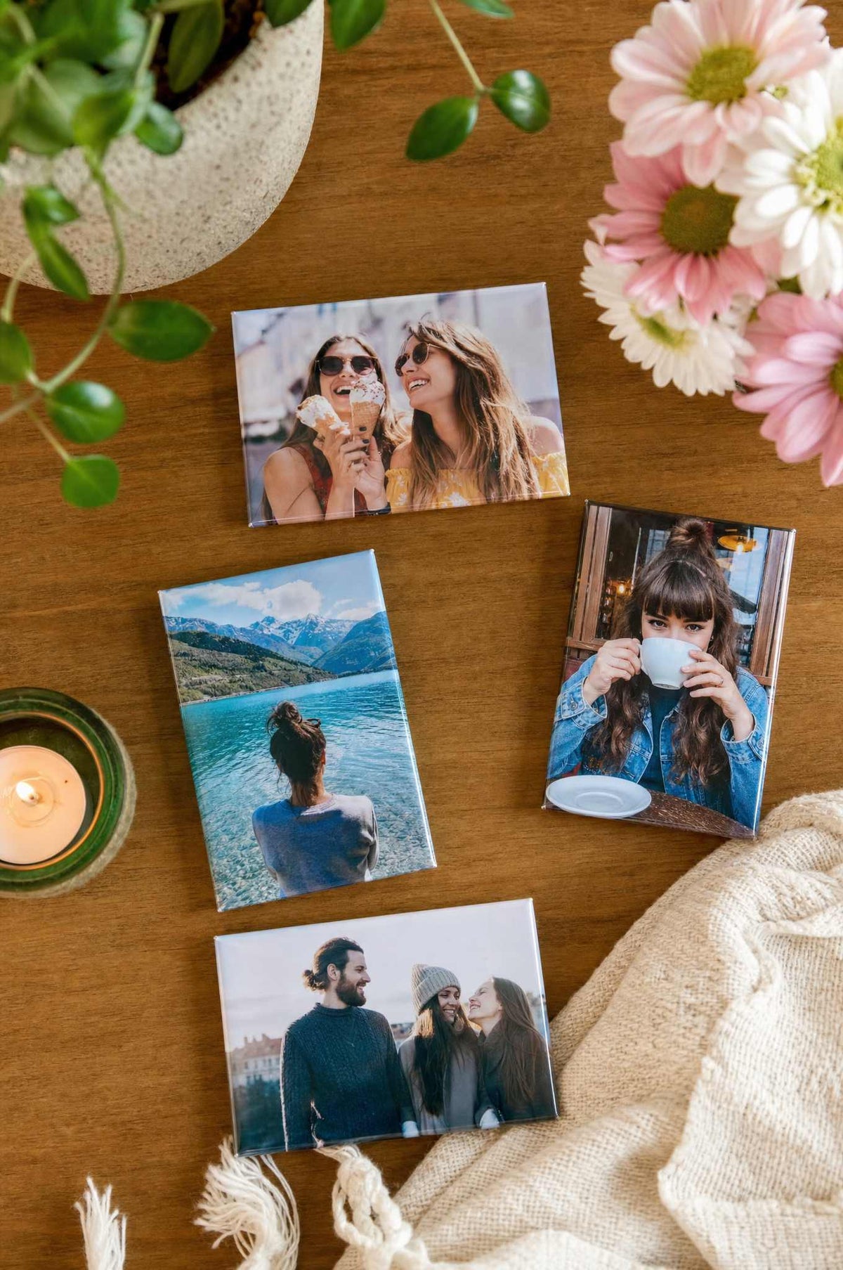 2x3 rectangle photo magnets scattered on a wooden table with flowers and a candle, couple and travel photos