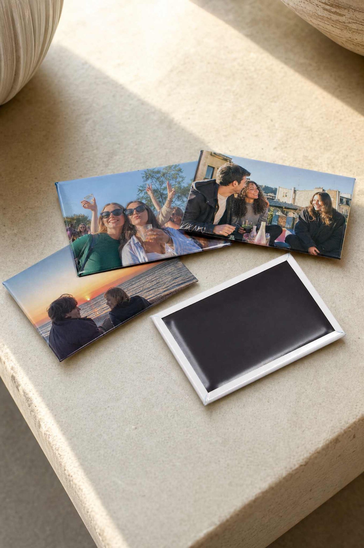 A stack of 2x3 photo magnets on a shelf with one turned over to show the magnetic back